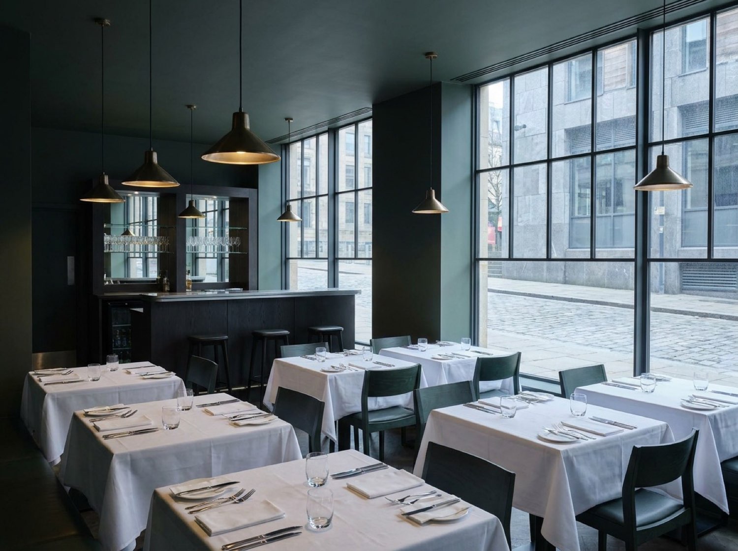 Sterling Crest Ledger Grill — set tables, low pendant lighting, dark green palette