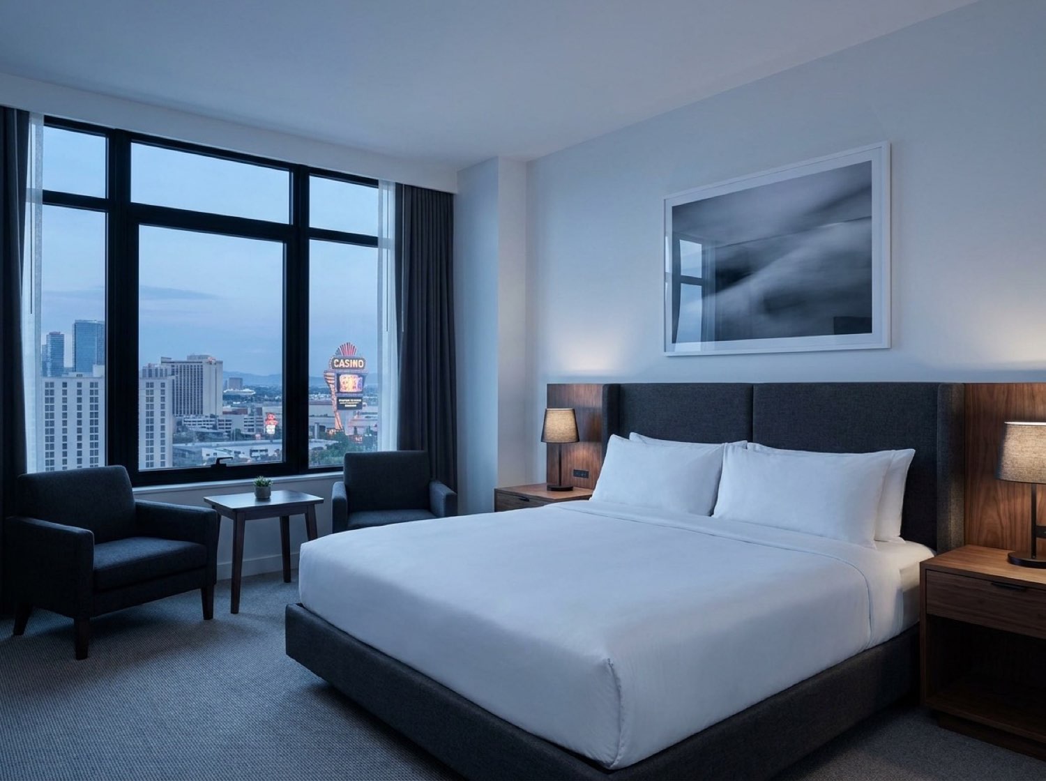 Sterling Crest suite interior — king bed, charcoal upholstery, city window